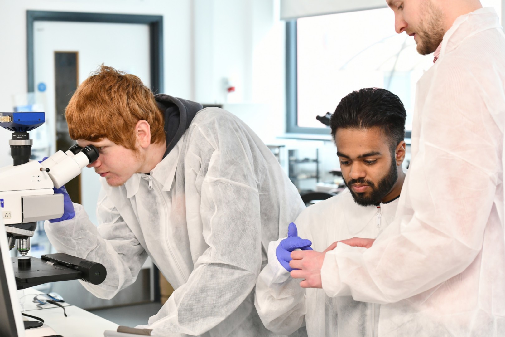 Two young people working in WMG lab, led by a Warwick staff member